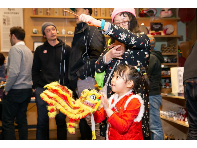 Little girl and her mother playing with a Chinese lion puppet