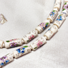 Close up of tube-shaped cloisonne design necklace - white
