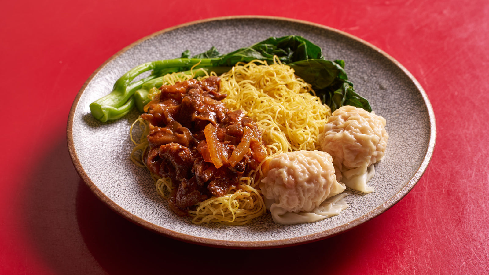 Dish with wontons, noodles with sauce, and Chinese broccoli